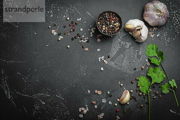 Nahaufnahme von traditionellen Kochzutaten: Knoblauch  Olivenöl  Salz  Pfeffer  frische Kräuter auf dunklem  rustikalem Hintergrund. Lebensmittelrahmen  Konzept für das Kochen gesunder Lebensmittel mit Platz für Text  Ansicht von oben