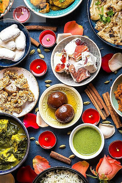 Festliches Essen für das indische Fest Diwali. Nahaufnahme. Naan  Samosa  Reis  Paneer  Süßigkeiten Holiday indischen Tisch mit Essen  Süßigkeiten  Blumen  brennende Kerzen. Diwali-Feierliches Abendessen. Verschiedenes indisches Essen