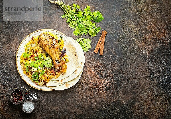 Eine Draufsicht auf BiryaniHuhn mit Basmatireis  Gemüse  Koriander und Naan Brot in einer Schüssel  ein traditionelles indisches würziges Gericht  auf rustikalem Steinhintergrund. Abendessen im indischen Stil  Platz für Text
