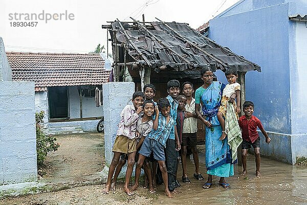 Eine Frau hält ihr Kind in der Hüfte und Kinder stehen im Regenwasser in einem Dorf  Tamil Nadu  Südindien  Indien  Asien