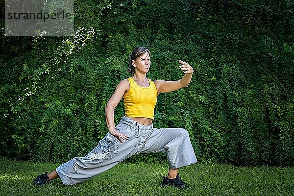 Frau übt Tai Chi im Freien. Frau kombiniert die Praxis des Chi Kung und der chinesischen Kampfkünste in einer natürlichen Umgebung  um seine Praxis und seine Verbindung zur Energie der Natur zu verbessern