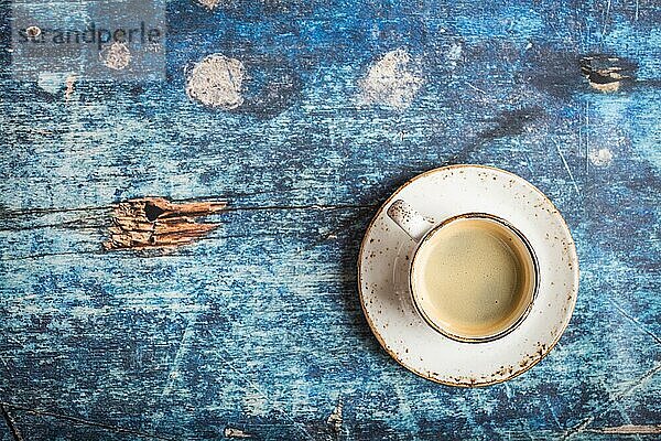 Tasse frischen heißen Kaffee auf alten rustikalen blaün Holztisch. Vintage-Hintergrund. Platz für Text. Morgenkaffee. Warmer schwarzer Kaffee. Espresso  weiße Tasse. Ansicht von oben. Nahaufnahme. Frisch zubereiteter Espresso