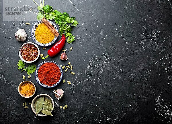 Indisches Essen Kochen Hintergrund. Traditionelle indische Gewürze und Zutaten. Curry  Kurkuma  Kardamom  Knoblauch  Pfeffer  frischer Koriander  Zimt. Zubereitung einer exotischen Mahlzeit. Ansicht von oben  Platz für Text