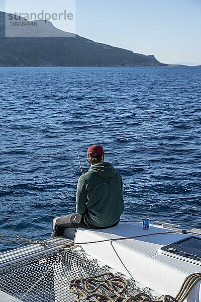 Junger Mann beim Angeln auf einem Segelboot  Segeltörn auf einem Segel-Katamaran  Dodekanes  Griechenland  Europa