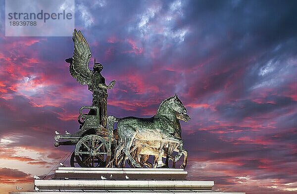 Die Quadriga der Einheit auf der Spitze einer der beiden Propyläen am Nationaldenkmal Viktor Emanuel II. (Vittoriano) bei Sonnenuntergang. Rom Italien