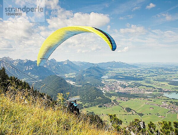 SCHWANGAU  DEUTSCHLAND 23. AUGUST: Unbekannter Gleitschirmflieger auf dem Tegelberg in Schwangau  Deutschland  am 23. August 2015. Der Tegelberg ist eines der beliebtesten Gleitschirmfluggebiete in Deutschland. Foto vom Tegelberg aufgenommen  Europa