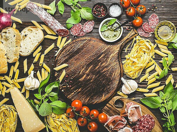Draufsicht auf italienische traditionelle Lebensmittel  Vorspeisen und Snacks wie Salami  Prosciutto  Käse  Pesto  Ciabatta  Olivenöl  Pasta auf rustikalem Holzbrett mit Platz für Text in der Mitte und Retro-Stil