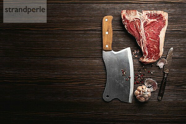 Draufsicht auf rohes  frisch marmoriertes Fleisch Steak T-Bone  rustikales Fleischbeil  Gewürze auf hölzernem Hintergrund mit Platz für Text. Kochen saftig Bio-Steak Metzgerei Konzept  gesunde saubere Ernährung  Nahaufnahme