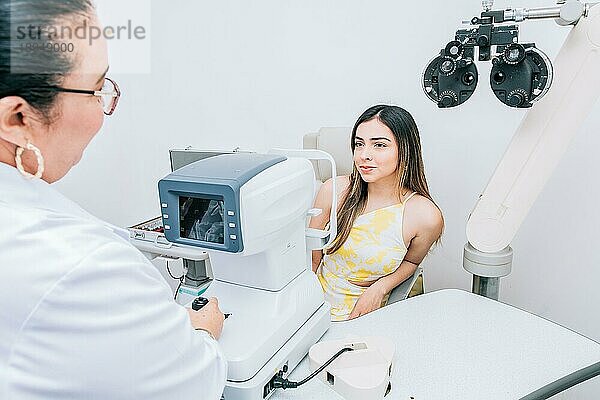 Patientin bei der Beratung durch einen Optiker in der Praxis. Optometrist mit Patientin im Autorefraktor