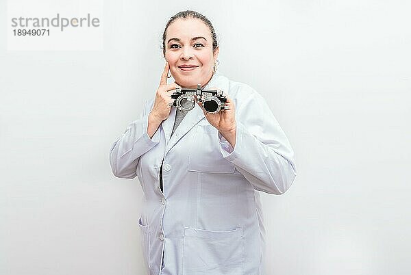 Lächelnder Augenarzt hält eine Messbrille isoliert. Portrait eines Optometristen  der eine Messbrille hält  isoliert
