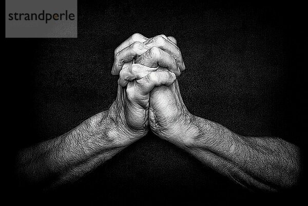 Männerhände mit gekreuzten Fingern. Dies ist eine klassische Geste einer Person  die in den christlichen Religionen zu Gott betet