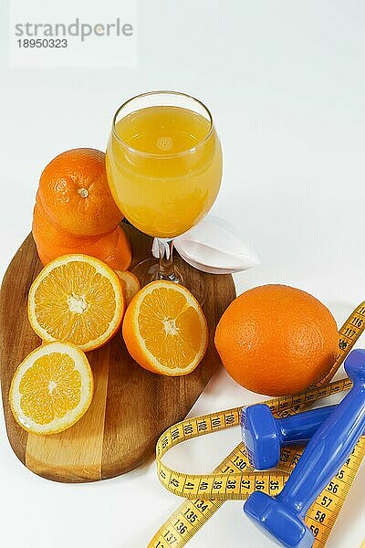 Natürliche Orangensaft mit Maßband und Hanteln auf einem Holzbrett und weißem Hintergrund. Konzept fitnes Gewichtsverlust
