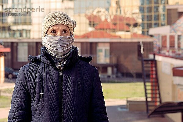 Eine arme ältere Frau trägt eine selbst gebastelte Maske  um sich vor Viren wie dem Coronavirus  auch bekannt als Covid19 oder SARS und MERS zu schützen. Sie befindet sich in einer städtischen Umgebung