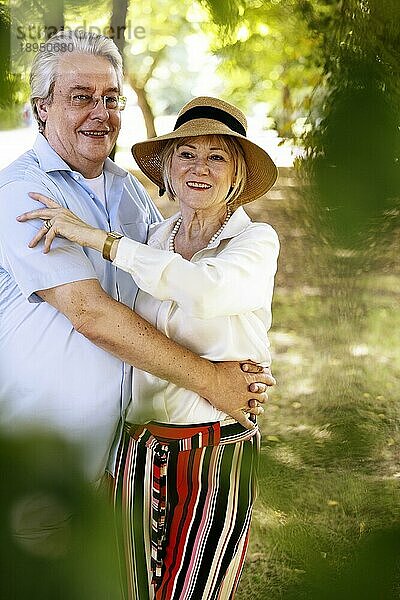 Deutschland  ältere Frau mit sommerlichem Strohhut im Park stehend zusammen mit ihrem Mann  Porträt  Europa
