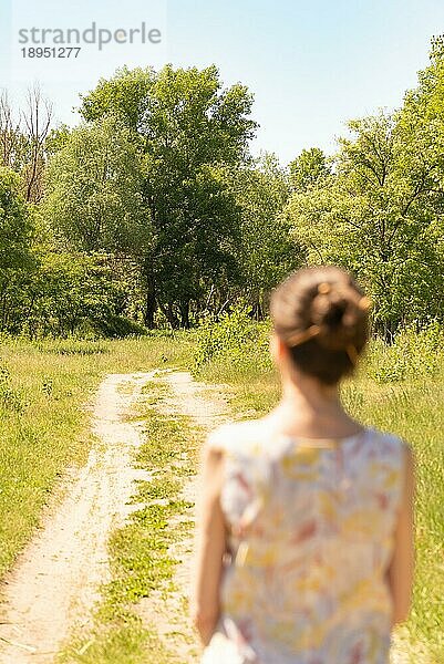 Eine Frau mit Dutt  die in Kiew  Ukraine  an der Landstraße steht  beobachtet die Bäume in der Ferne. Die Silhouette der Frau ist unscharf  vor einem fokussierten Hintergrund  Europa