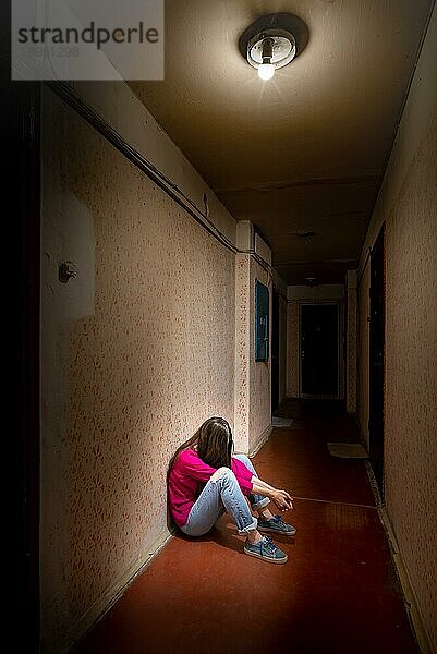Eine traurige und verzweifelte Frau sitzt in einem dunklen Korridor  der von einem düsteren Licht erhellt wird. Ihr Schmerz und ihre vielen Probleme haben sie in die völlige Isolation getrieben. Seine Traurigkeit wird nur noch durch seine Einsamkeit übertroffen