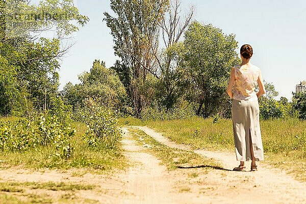 Eine Frau mit Dutt  die in Kiew  Ukraine  an der Landstraße steht  beobachtet die Bäume in der Ferne. Die Silhouette der Frau ist unscharf  vor einem fokussierten Hintergrund  Europa