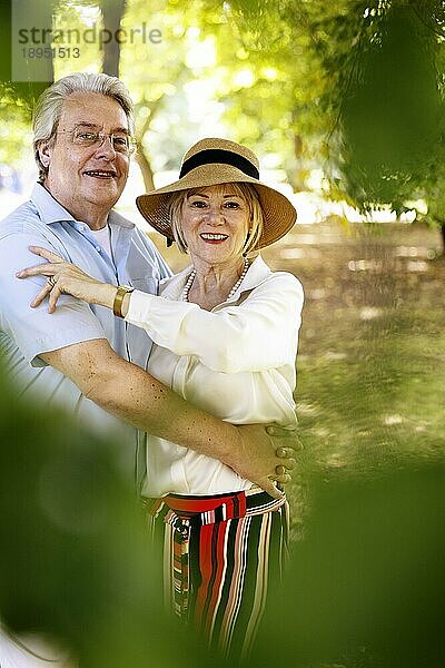 Deutschland  ältere Frau mit sommerlichem Strohhut im Park stehend zusammen mit ihrem Mann  Porträt  Europa