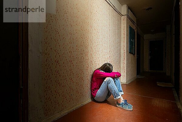 Eine traurige und verzweifelte Frau sitzt in einem dunklen Korridor  der von einem düsteren Licht erhellt wird. Ihr Schmerz und ihre vielen Probleme haben sie in die völlige Isolation getrieben. Seine Traurigkeit wird nur noch durch seine Einsamkeit übertroffen