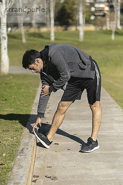 Attraktiver sportlicher Mann bei einer Dehnungsübung  Vorbereitung auf das morgendliche Training im Park