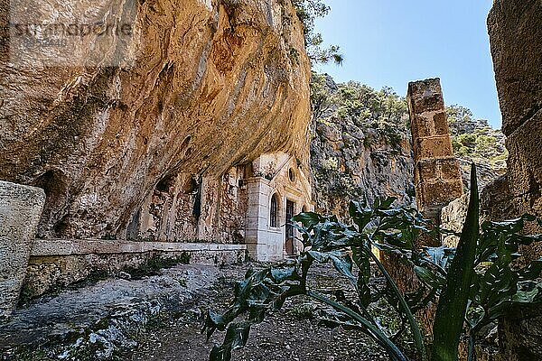 Orthodoxe Höhlenkirche des Heiligen Johannes des Einsiedlers im verlassenen Kloster Katholiko in der Avlaki Schlucht  Halbinsel Akrotiri  Chania  Kreta  Griechenland. Frühlingsaufnahme des Eingangs und des Weges dorthin bei Tageslicht. Selektiver Fokus