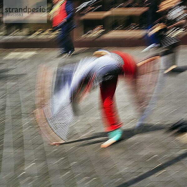 Bunter Clown schlägt ein Rad  turnt  Radschlag  Passanten in der Fußgängerzone  Symbolbild Freude  Lebensfreude  Spontanität  spontan  Bewegungsunschärfe  Bielefeld  Deutschland  Europa