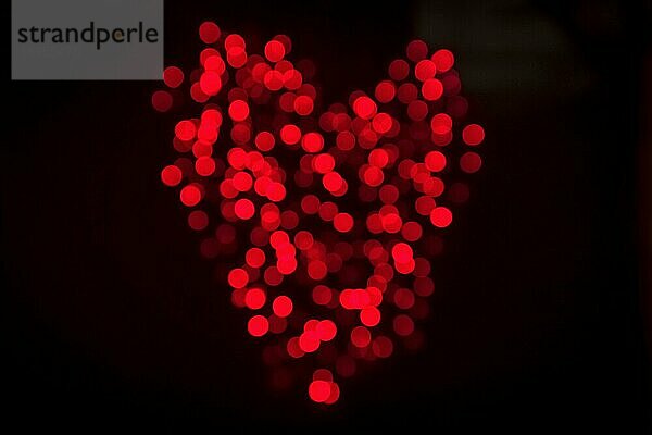 Herz aus glänzenden Bokeh Lichter in roter Farbe auf einem dunklen Hintergrund am Valentinstag gemacht