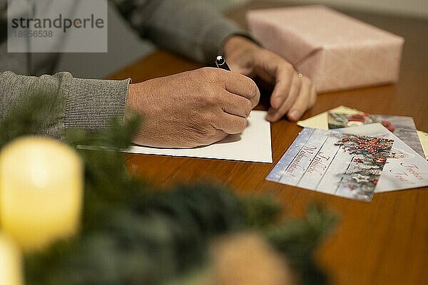 Fröhliche Weihnachten. Mann schreibt Weihnachtskarten per Hand. Handschrift