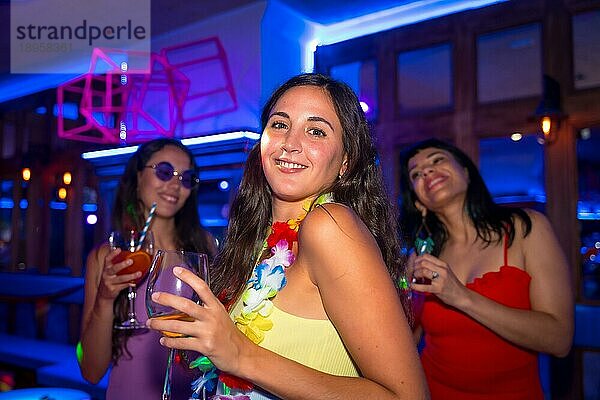 Portrait attraktive Frau lächelnd mit einem Glas Alkohol in einem Nachtclub auf einer Nachtparty