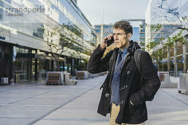 Ein gutaussehender Geschäftsmann telefoniert in der Nähe seines Büros mit seinem Handy. Leerzeichen kopieren