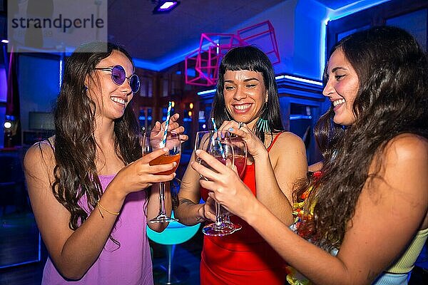 Porträt attraktive Frauen stoßen an und haben Spaß mit Getränken in Disco Club bei Sommernachtsparty im Pub