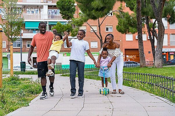 Familie schwarzafrikanischer Herkunft mit Kindern auf dem Spielplatz  lächelnd am Schulausgang