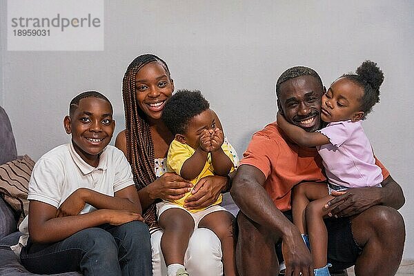 Porträt einer schwarzafrikanischen Familie mit Kindern auf dem Sofa zu Hause  die Spaß haben
