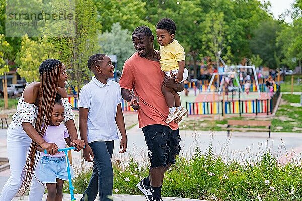 Familie schwarzafrikanischer Herkunft mit Kindern auf dem Spielplatz  lächelnd am Schulausgang