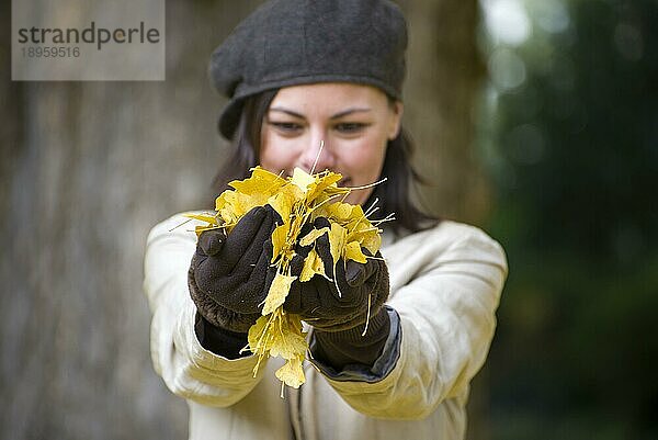 Glückliche Frau mit Hut und gelben Herbstblättern