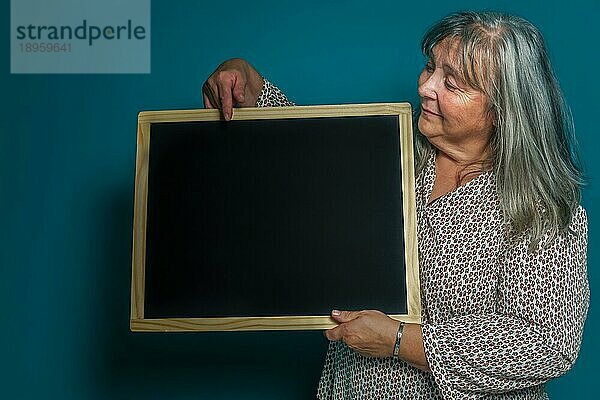 Ältere weißhaarige Frau hält eine Tafel mit Platz zum Kopieren von Text