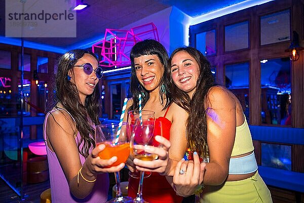 Porträt attraktive Frauen stoßen mit Gläsern im Nachtclub bei einer Sommernachtsparty im Pub an