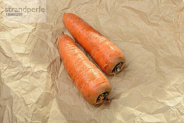 Zwei schöne natürliche Karotten auf einem braunen Stück Bastelpapier