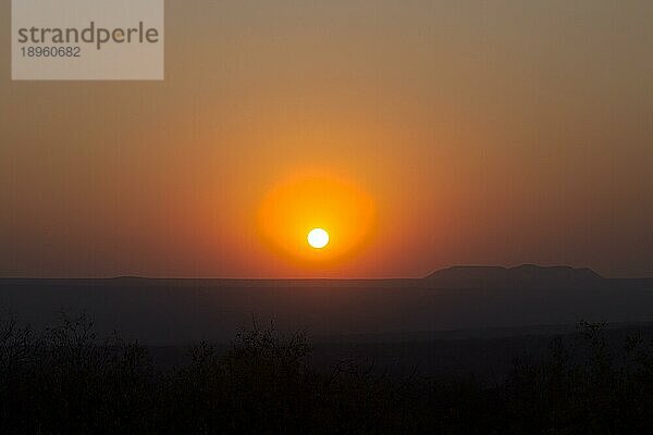 Roter Sonnenuntergang über einer großen Fläche mit Hügeln und Klippen im indischen Sommer