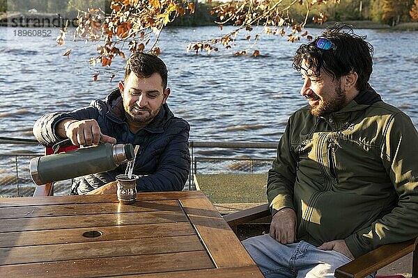 Zwei Freunde genießen den Sonnenuntergang beim Mate trinken