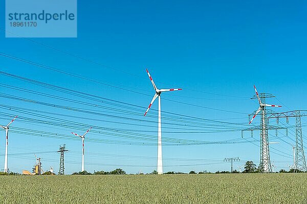 Windenergieanlagen und Stromübertragungsleitungen an einem sonnigen Tag in Deutschland