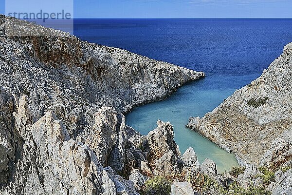 Vertikaler Blick auf eine z förmige Bucht in einer typischen griechischen oder kretischen Sommerlandschaft an einem sonnigen Tag. Großer blauer Himmel und schöne Wolken. Scharfe Kalksteinfelsen im unscharfen Vordergrund. Selektiver Fokus. Seitan Limania  Akrotiri  Chania  Insel Kreta  Griechenland  Europa