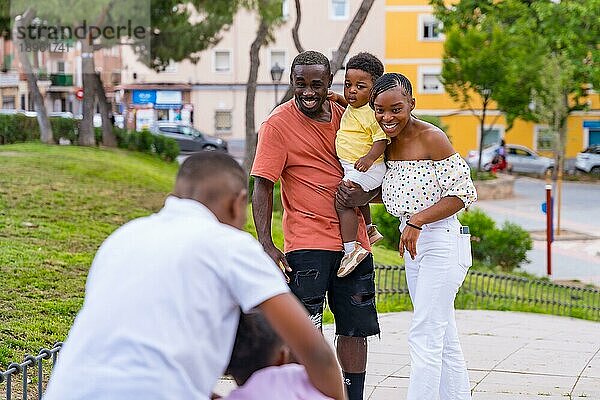 Afrikanische schwarze ethnische Familie  die Spaß mit glücklichen Kindern zusammen im Stadtpark hat