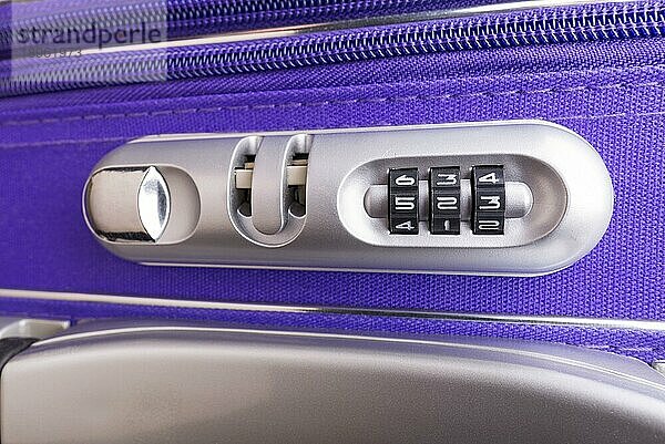 Nahaufnahme eines Sicherheitsschlosses mit drei Zahlen an einem violetten reisefertigen Koffer im Safe