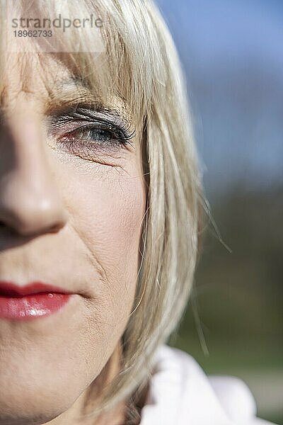 Geschminkter Transvestit mit blonder Perücke im Park  Gesicht im Anschnitt  Portrait  Köln  Nordrhein-Westfalen  Deutschland  Europa