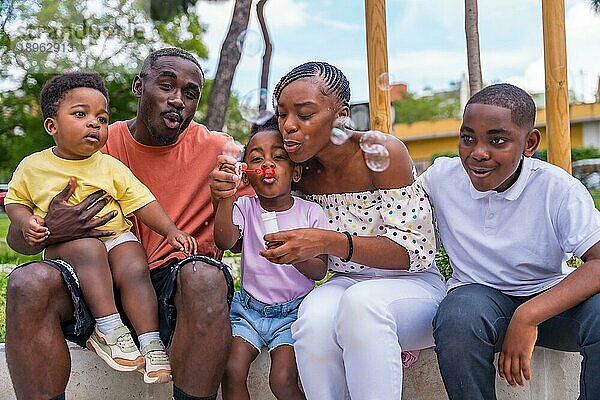 Afrikanische schwarze ethnische Familie mit Kindern auf dem Spielplatz  die Seifenblasen blasen