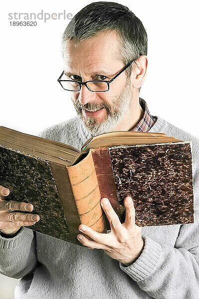 Ein lächelnder Mann  der ein altes Buch liest und eine Brille trägt
