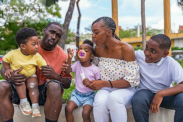 Afrikanische schwarze ethnische Familie mit Kindern auf dem Spielplatz  die Seifenblasen blasen