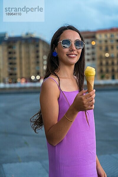 Porträt der jungen brünetten Frau lächelnd essen ein Mangoeis neben dem Strand im Sommerurlaub