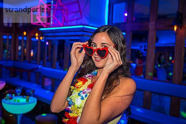 Attraktive lateinamerikanische Frau auf einer Nachtparty in einer Disco mit Gläsern voller Herzen